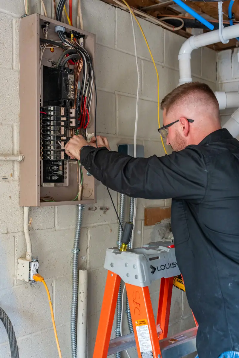 Tim Sky testing circuits at an exterior electrical panel